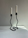 black metal candles stick that holds two standard tapers. Base has undulating waved design to metal.