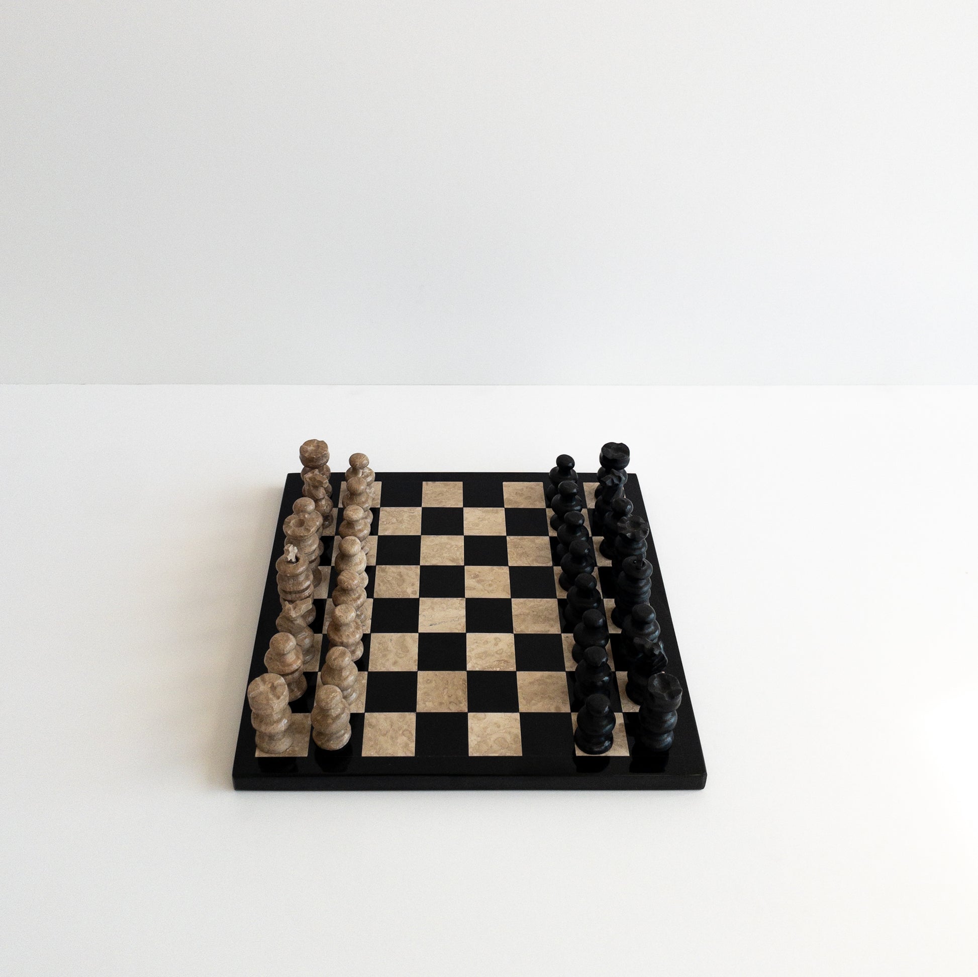 natural marble chess pieces arranged on stone board